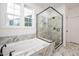 Bright bathroom with a glass enclosed shower and tub, marble tile, and modern fixtures at 1205 Porters Call Dr, Wendell, NC 27591