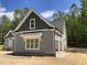 Side view of gray house featuring a garage and stone detailing, set against a backdrop of lush trees at 1224 Red Cedar Ct # 33, Youngsville, NC 27596