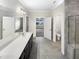 Spacious bathroom with a double sink vanity, large mirror, walk-in shower, tile floor, and open doorway to bedroom at 154 Magenta Rose Dr, Raleigh, NC 27610