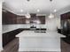 Bright kitchen features a large center island, stainless steel appliances, dark wood cabinetry, and modern pendant lights at 154 Magenta Rose Dr, Raleigh, NC 27610