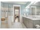 Bright bathroom features a dual sink vanity, walk-in shower with tile accents, and views of the bedroom at 175 Stonecrest Way, Pittsboro, NC 27312