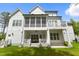 Expansive view of a white farmhouse-style home with a screened porch, balcony and lawn at 175 Stonecrest Way, Pittsboro, NC 27312