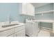 Clean laundry room with white cabinets, countertop sink, washer, dryer, and storage space, all accented by blue walls at 175 Stonecrest Way, Pittsboro, NC 27312