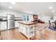 This kitchen features stainless appliances, white cabinets, wood floors, and island with seating, adjacent to living space at 2502 Devils Racetrack Rd, Four Oaks, NC 27524