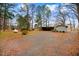 A gravel driveway leads past a small outbuilding, showcasing the expansive lot with mature trees at 2502 Devils Racetrack Rd, Four Oaks, NC 27524
