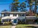 Charming two-story home featuring white siding, black shutters, mature trees, and a convenient attached carport at 304 Northbrook Dr, Raleigh, NC 27609