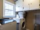 Functional laundry room with modern washer and dryer, storage cabinets, and a bright window at 304 Northbrook Dr, Raleigh, NC 27609
