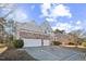 Inviting two-story home featuring a stone facade, a three-car garage, a manicured lawn and traditional design elements at 309 Malvern Hill Ln, Morrisville, NC 27560