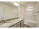 Bathroom featuring double granite countertop vanity, a large mirror, and tub with white tile at 3505 Triad Ct, Raleigh, NC 27604