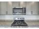 Close-up shot of stainless steel microwave and oven with granite countertops and gray cabinetry at 3505 Triad Ct, Raleigh, NC 27604