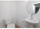 Half bath with a round mirror, pedestal sink, and a toilet at 3928 Willow Gate Way, Raleigh, NC 27604