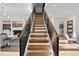 Modern staircase with hardwood steps, black railing, white risers and stringers, and views of the living room at 4329 Lambeth Dr, Raleigh, NC 27609