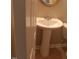 Close-up of pedestal sink in a bathroom; features tiled flooring and gold-trimmed mirror at 711 Weathervane Way, Rocky Mount, NC 27803
