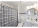 Bathroom featuring a shower and tub, single sink vanity, round mirror and three globe light fixture at 1011 Lowry Ave, Durham, NC 27701