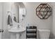 Powder room with pedestal sink, decorative mirror and shelves, and modern fixtures at 1014 Falling Rock Pl, Durham, NC 27703
