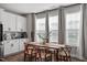 Bright dining area with a wood table, six chairs, white cabinets, and multiple windows with gray curtains at 1014 Falling Rock Pl, Durham, NC 27703