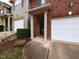 Close-up of a brick townhome entrance with covered porch and well-kept landscaping at 102 Forrymast Trl, Apex, NC 27539