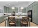 Open kitchen with green cabinetry, white countertops, a large island with seating and modern lighting fixtures at 1105 Lowland St, Apex, NC 27523