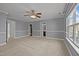 A large bedroom with neutral carpet, grey walls, white trim, ceiling fan, natural light, and two entryways at 1217 Maroon Dr, Durham, NC 27713