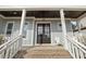 Inviting front porch with brick steps, white railings, and black double doors with glass panels at 1421 Sweetclover Dr, Wake Forest, NC 27587