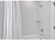 Clean bathroom with a tub and shower featuring white marble-style tile and a modern showerhead, exuding elegance at 1421 Sweetclover Dr, Wake Forest, NC 27587