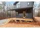 Modern black home features a wood porch and trim, metal railings and a landscape of trees and pine straw at 168 Daphine Dr, Hillsborough, NC 27278