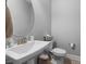 Neat half bathroom with a stylish vessel sink, round mirror, and neutral wall color at 176 E Ravano Dr, Clayton, NC 27527