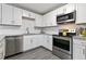Updated kitchen with stainless steel dishwasher, granite countertops, white cabinets, and gray flooring at 2305 Fitzgerald Ave, Durham, NC 27707