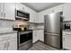 Well-equipped kitchen with stainless steel appliances, white cabinets, granite countertops, and gray flooring at 2305 Fitzgerald Ave, Durham, NC 27707