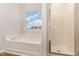 Bright bathroom showcasing a soaking tub, glass-enclosed shower, and a large window with neighborhood views at 3020 Buttonwood Ln, Clayton, NC 27520