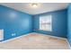 Neutral carpeted bedroom with bright blue walls and natural light from a window at 4909 Jelynn St, Raleigh, NC 27616