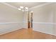 Neutral-toned dining area featuring hardwood floors, wainscoting detail, and elegant lighting fixture at 4909 Jelynn St, Raleigh, NC 27616