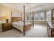 Inviting main bedroom features a four-poster bed, a tray ceiling, and lots of natural light from large windows at 5000 Sears Farm Rd, Cary, NC 27519