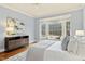 Comfortable bedroom featuring a large window, sitting bench, hardwood floors, and soft lighting at 5204 Winter Holly Ct, Raleigh, NC 27606