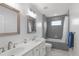 Bright bathroom features double sinks, stylish mirrors, and a bathtub with gray tile surround at 5512 Spring Bluffs Ln, Raleigh, NC 27606