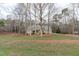 View of a brick home nestled among mature trees and a sprawling front lawn, creating a serene setting at 5512 Spring Bluffs Ln, Raleigh, NC 27606