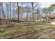 Spacious backyard with mature trees and iron fence and a view of surrounding homes at 6065 Merion Cir, Sanford, NC 27332