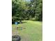 A grassy backyard with scattered trees offers ample outdoor space and two plastic barrels at 652 Old Sanford Rd, Moncure, NC 27559