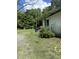 Shows the side exterior with a small covered porch, green bushes, and a gravel driveway at 652 Old Sanford Rd, Moncure, NC 27559