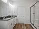 Well-lit bathroom featuring double sinks, granite countertops, wood-look flooring, and a glass-enclosed shower at 962 Spring Hill Church Rd, Lillington, NC 27546
