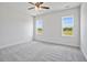 Bright bedroom showcasing two large windows, neutral walls, plush carpeting, and a ceiling fan at 962 Spring Hill Church Rd, Lillington, NC 27546