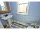 Charming powder room featuring blue walls, pedestal sink and decorative mirror at 1005 Whistler St, Durham, NC 27713