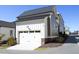 Side view of a two-car garage with white doors, a grey roof, and taupe siding at 1005 Whistler St, Durham, NC 27713
