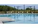 Relaxing poolside lounge area with shaded seating and clear blue water reflecting the sky at 101 Hiddenite Pl, Holly Springs, NC 27540