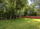 Expansive green backyard enclosed by a red fence and featuring mature trees at 104 Pinecroft Dr, Raleigh, NC 27609