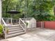 Spacious backyard deck with patio seating, a dining set, a patio umbrella, and a storage shed at 104 Pinecroft Dr, Raleigh, NC 27609