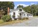 Exterior side view of a charming white farmhouse-style home with a metal roof and covered porch at 105 D Hart Rd, Siler City, NC 27344