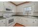 Bright kitchen with white appliances, cabinets, and a window providing natural light at 1103 Driftwood Dr, Siler City, NC 27344