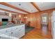 Cozy living area with a fireplace and wood paneling seamlessly flowing into the kitchen with modern appliances at 1103 Driftwood Dr, Siler City, NC 27344