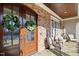 Elegant front door with glass panels and decorative wreaths, leading to a welcoming porch with comfortable seating at 113 Hardy Oaks Way, Holly Springs, NC 27540